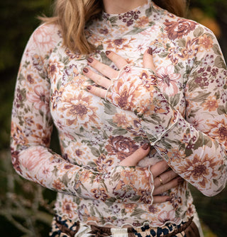 Model wears a long-sleeved pastel floral print top with wavy hems and a mock neckline