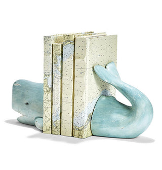 Distressed-effect blue sperm whale bookends support a vertical stack of four books with cartographic covers