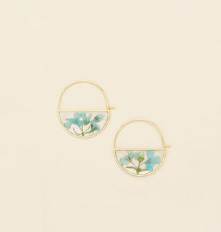 Gold hoop earrings with bottom semicircles containing resin-encased pressed blue flowers and green stems and leaves