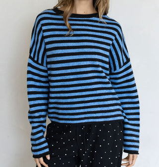 Model wears a black and blue striped sweater with black and white micro-polka dot pants