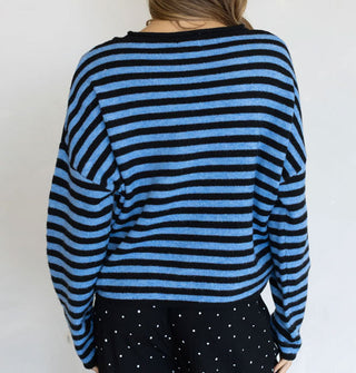 Model facing away from the camera wears a black and blue striped sweater with black and white micro-polka dot pants