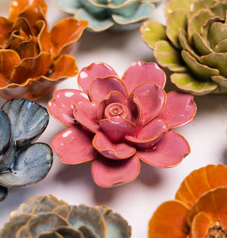 Blush pink Tahitian gardenia ceramic flower wall art sculpture with yellowish edges surrounded by other colors and styles