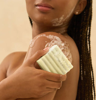 Model lathers a bar of soap on shoulder