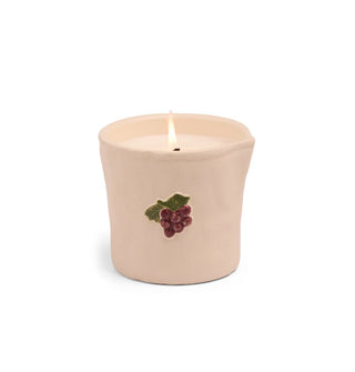 Rustic light peach-pink ceramic candle jar with hand-painted embossed bunch of grapes graphic and single lit wick inside