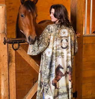 Model standing in front of a horse's stall wears a long, kimono-style robe with horse motif and the words, "Born to run" in a banner near the top