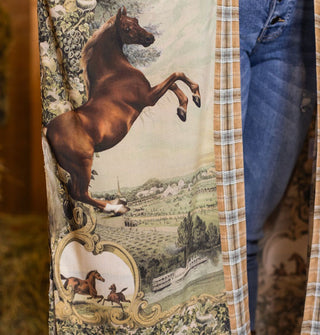 Closeup of the detail on a kimono-style robe featuring an enlarged bucking horse against a pastoral scene and above other horses inside an ornate frame
