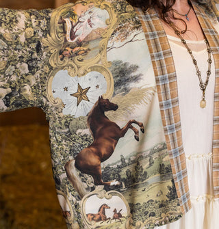 Closeup of a rearing brown horse on an open-front tunic with scroll, star, and landscape patterns