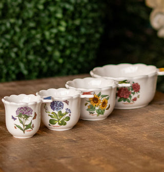 Set of four white ceramic measuring cups featuring floral designs and butterfly-shaped handles