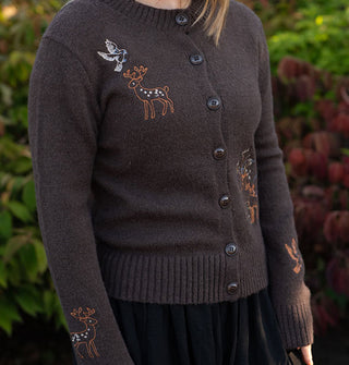 Model wears a brown long-sleeved button-down cardigan with colorful deer, bird, and plant embroidery on its bodice and sleeves