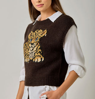 Model wears a brown sweater vest with blue-eyed leopard cub graphic over a white collared button-down shirt