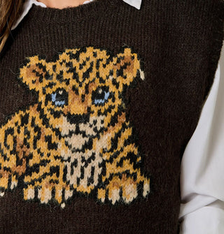 Closeup of the blue-eyed leopard cub graphic on a brown sweater vest worn over a white button-down shirt