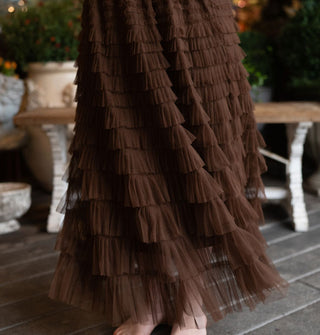 Model wears a multi-tiered ruffled brown tulle maxi skirt