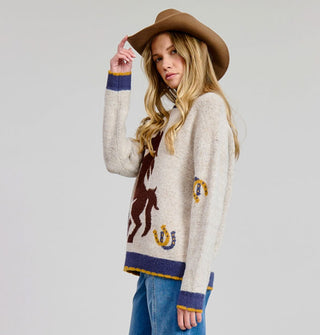 Model wears a beige sweater with brown rearing horse graphic in the center flanked by horseshoes and finished with a blue and yellow border on the sleeve cuffs and bottom hem