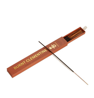 Dark orange slide box of Burnt Clementine incense sticks with white ribbon pull tab and metallic gold lettering