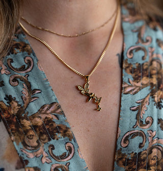 Model in a sumptuously printed robe wears a gold necklace with butterfly cluster pendant