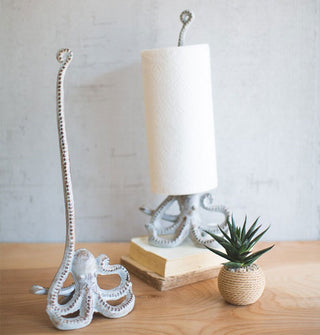 Silver-toned octopus-shaped paper towel holders, one with a roll of paper towels on it and the other without, staged with a small succulent