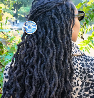 Model wears a caviar claw clip in partially pulled-back dreadlocks