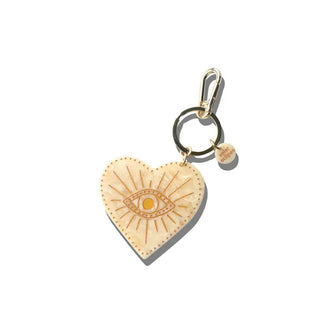Cream-colored quartz-effect heart-shaped charm with gold-accented radiant eye etching hangs from a gold keyring with tab and lobster clasp attached