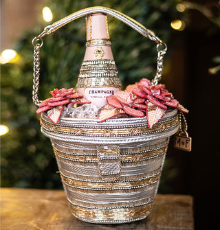 Beaded handbag with partial chain strap is designed to resemble an ice bucket with a bottle of champagne inside flanked by pink flowers