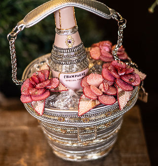 Beaded handbag with partial chain strap is designed to resemble an ice bucket with a bottle of champagne inside flanked by pink flowers