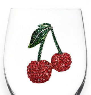 Closeup of a red and green rhinestone-encrusted cherries decal on the bowl of a clear wine glass
