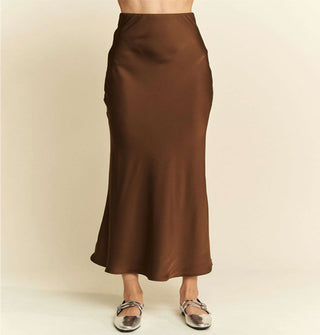 Model wears a brown satin midi-length skirt with silver Mary Janes