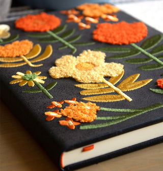 Closeup of the plush, embroidered flower designs on a dark gray journal hardcover
