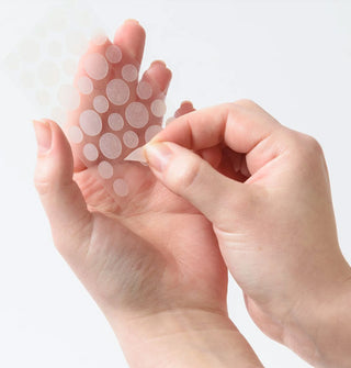 Model holds a sheet of hydrocolloid pimple patches in hand and peels one patch off of the sheet