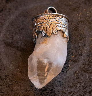 Curved chunk of clear crystal quartz in a decorative silver necklace pendant setting