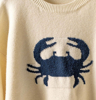 Closeup of navy blue grab graphic on a cream-colored sweater with ribbed neckline