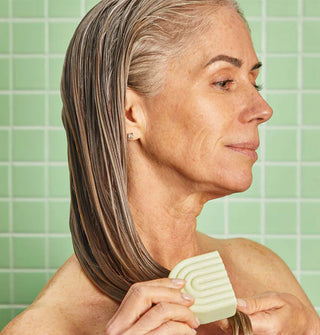 Model applies a conditioner bar to damp hair lengths