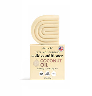 Light yellow C-shaped ribbed bar of Kitsch Deep-Moisturizing Solid Coconut Oil Conditioner sits atop its box packaging