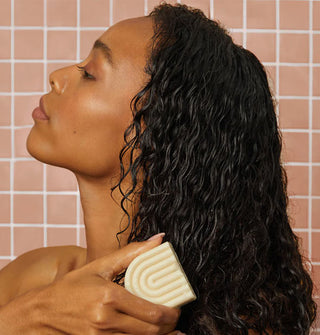 Model applies a solid conditioner bar to the ends of hair