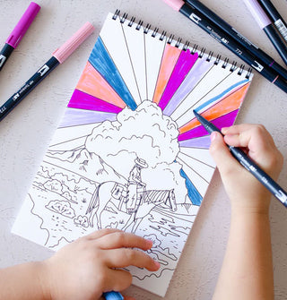 Model colors in a picture in the Cosmic Cowgirl Coloring Book depicting a cowgirl on horseback against a radiant sky