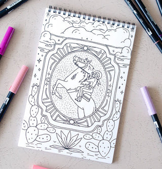 Line drawing of a cowgirl riding a bucking bronco in a spiral-bound coloring book flanked by markers