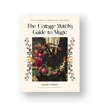 White cover of The Cottage Witch's Guide to Magic by Suzanne Lemmon features a central image of a floral crescent moon wreath hanging from strips of white fabric and flanked by illustrated floral borders