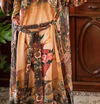 Model wears a long belted robe with sacred heart design and lush florals