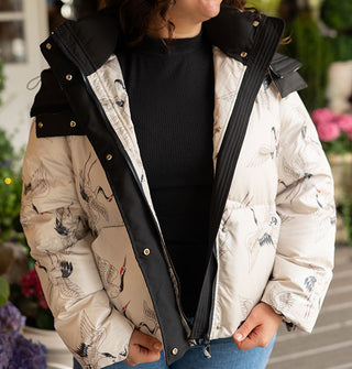 Model wears an open white crane print puffer jacket with black trim and snap buttons