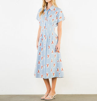 Model wears a short-sleeved blue pinstripe midi shirt dress with collar and a print of lobsters in white ovals