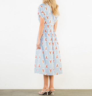 Model wears a short-sleeved blue pinstripe midi shirt dress with collar and a print of lobsters in white ovals