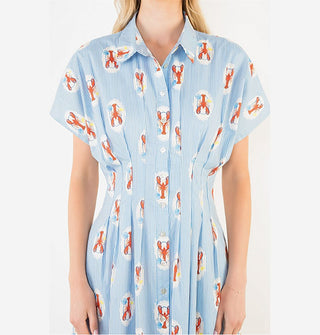 Model wears a short-sleeved button-down blue pinstripe shirt dress and a print of lobsters in white ovals