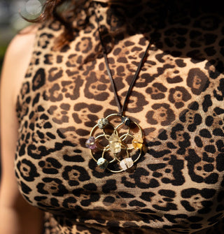 Model in leopard print tank top wears a seed of life pendant necklace with crystals wired to its points strung on leather cord