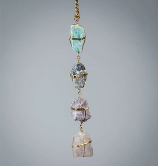 Four rough-cut gemstones wrapped in gold wire on a gold curb chain