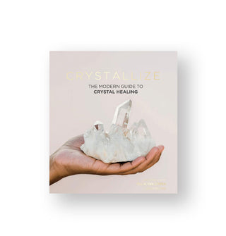 Cover of Crystallize: The Modern Guide to Crystal Healing features some metallic foil lettering and an image of a hand holding a quartz cluster