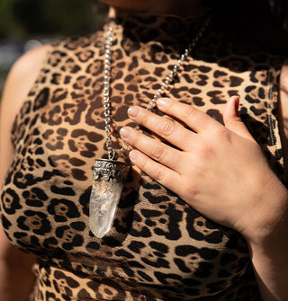 Model in leopard print top touches the silver chain of a clear crystal point pendant necklace she is wearing
