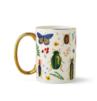 White mug with gold rim and handle features colorful designs of insects and flowers