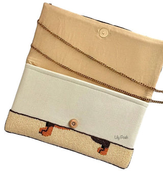 Clutch interior reveals bottom portion of exterior beaded dachshund design, a snap button closure, and chain strap