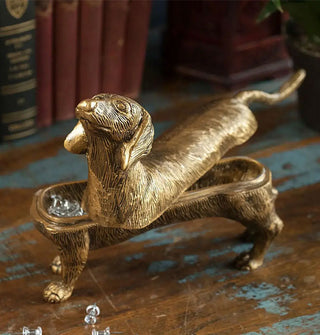 Gold-toned dachshund box with lid set askew on top to reveal baubles inside