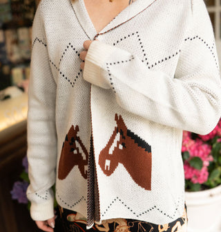 Model wears a long-sleeved white cardigan with diamond and zigzag detail designs and two brown mirrored horsehead graphics