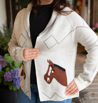 Model wears a long-sleeved white cardigan with diamond and zigzag detail designs and two brown mirrored horsehead graphics